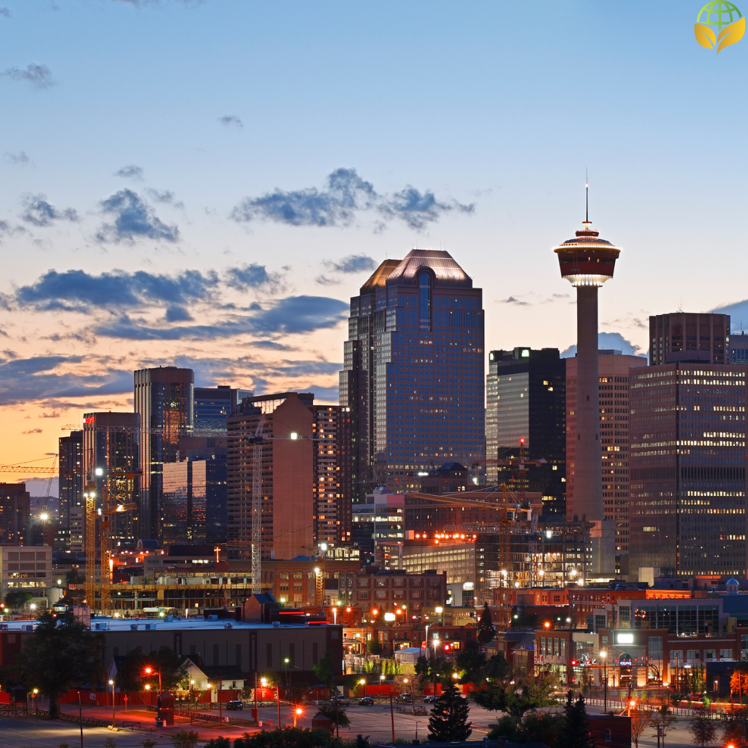 A picturesque view of Calgary's skyline at dusk, showcasing the city's iconic buildings and the Calgary Tower prominently. The image captures the urban landscape lit up against the evening sky, reflecting the city's vibrant life and architectural beauty.